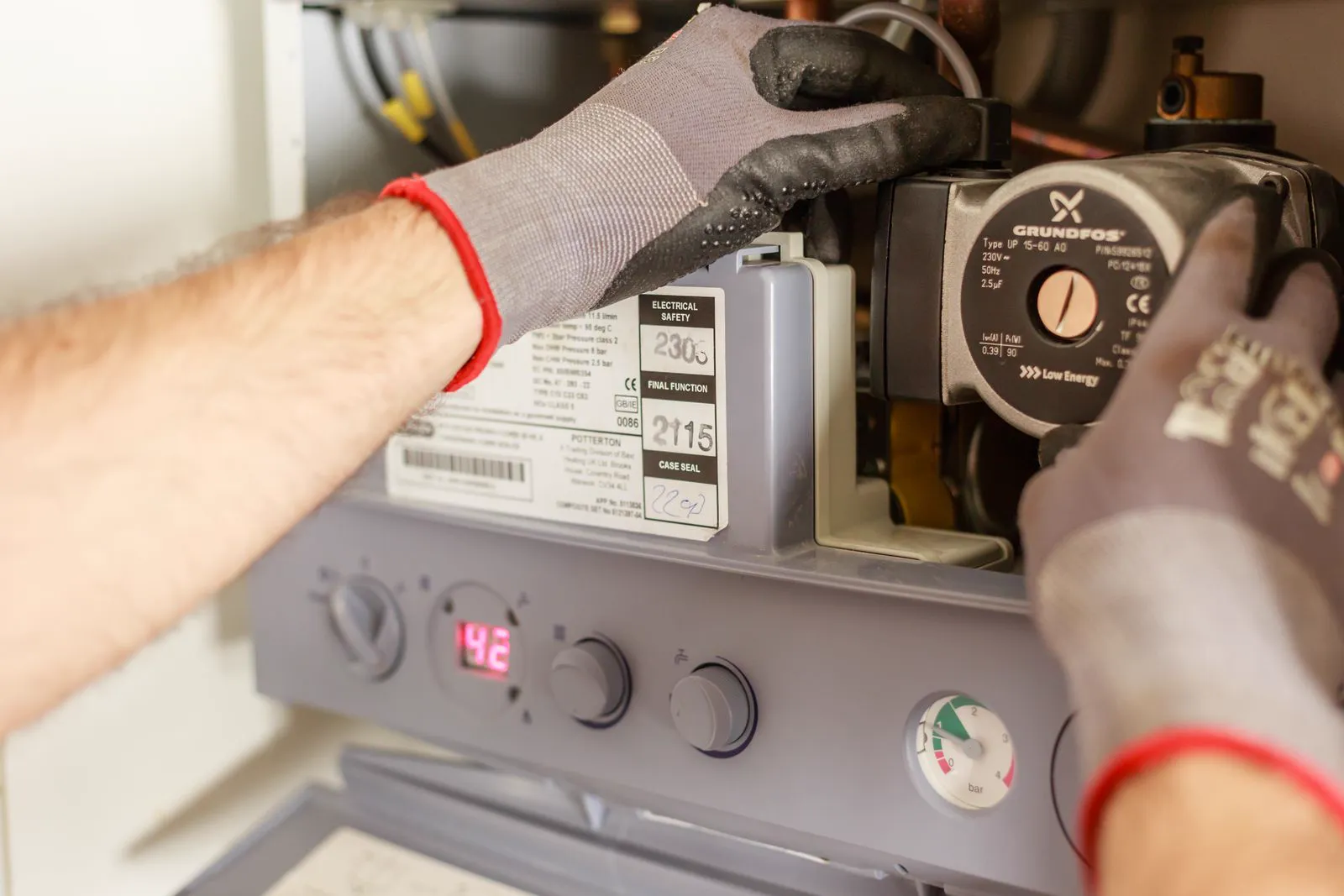 Gloved hands servicing a residential boiler heating system